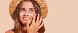letnia-pielęgnacja-twarzy-usmiechnieta-kobieta-w-kapeluszu-z-kremem