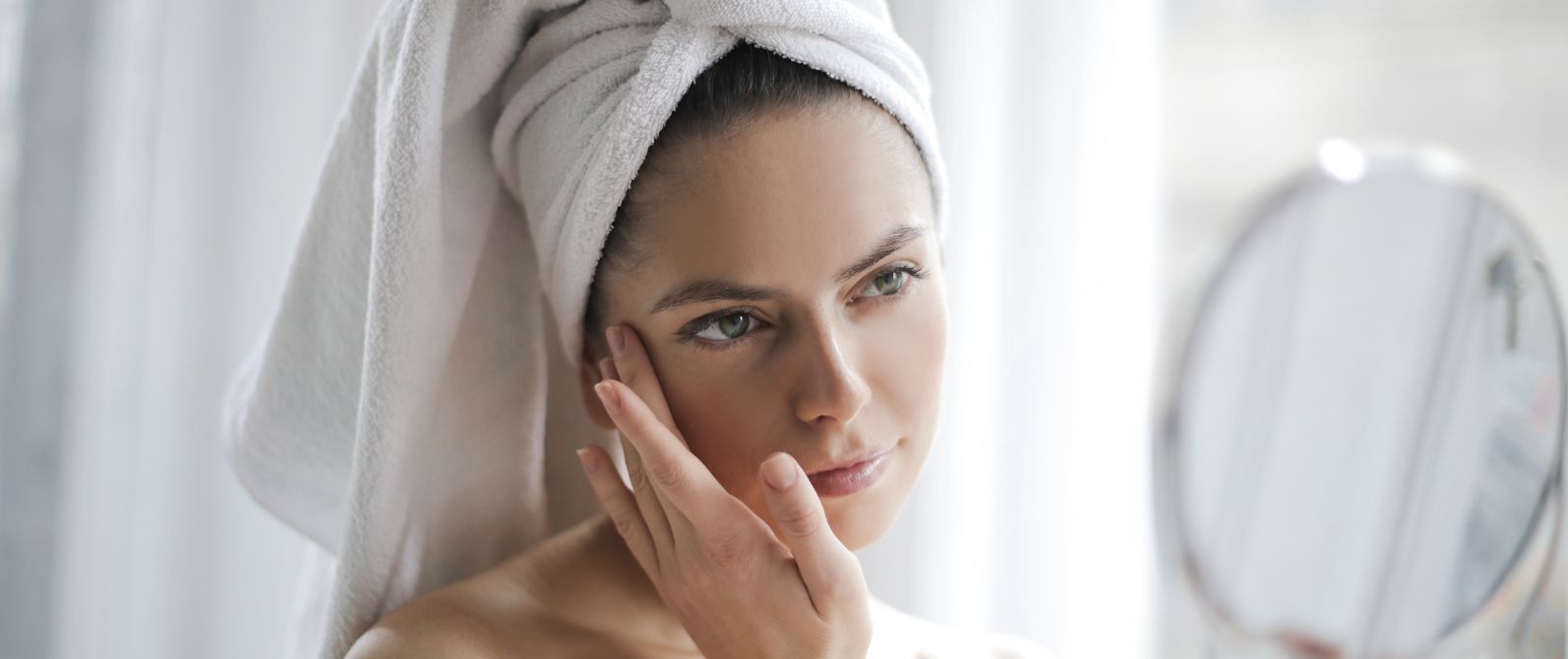 pielęgnacja-skóry-tłustej-kobieta-trzymajaca-lusterko